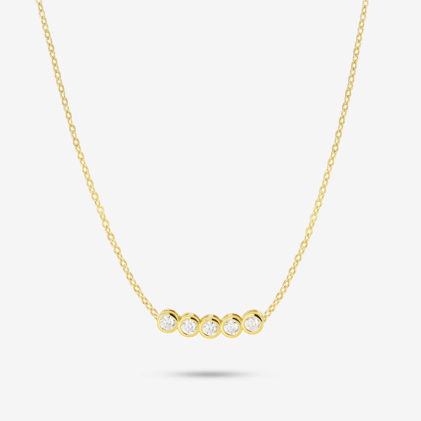 Studio shot of the Gold Dawn Necklace featuring five round bezel-set moissanites aligned horizontally on a delicate yellow gold chain, displayed on a light grey background