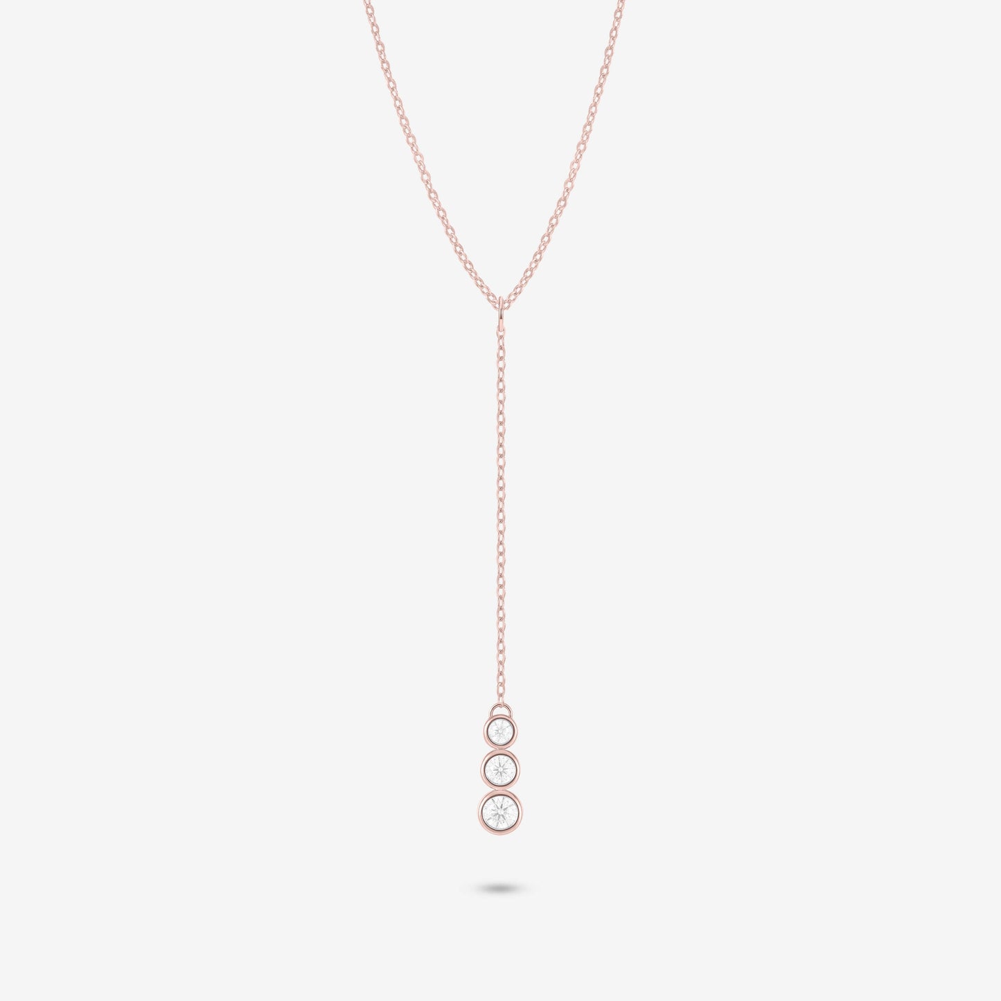 Studio shot of the Rose Gold Astral Necklace with a trio of graduated bezel-set moissanites in a vertical drop pendant design, shown against a neutral grey background