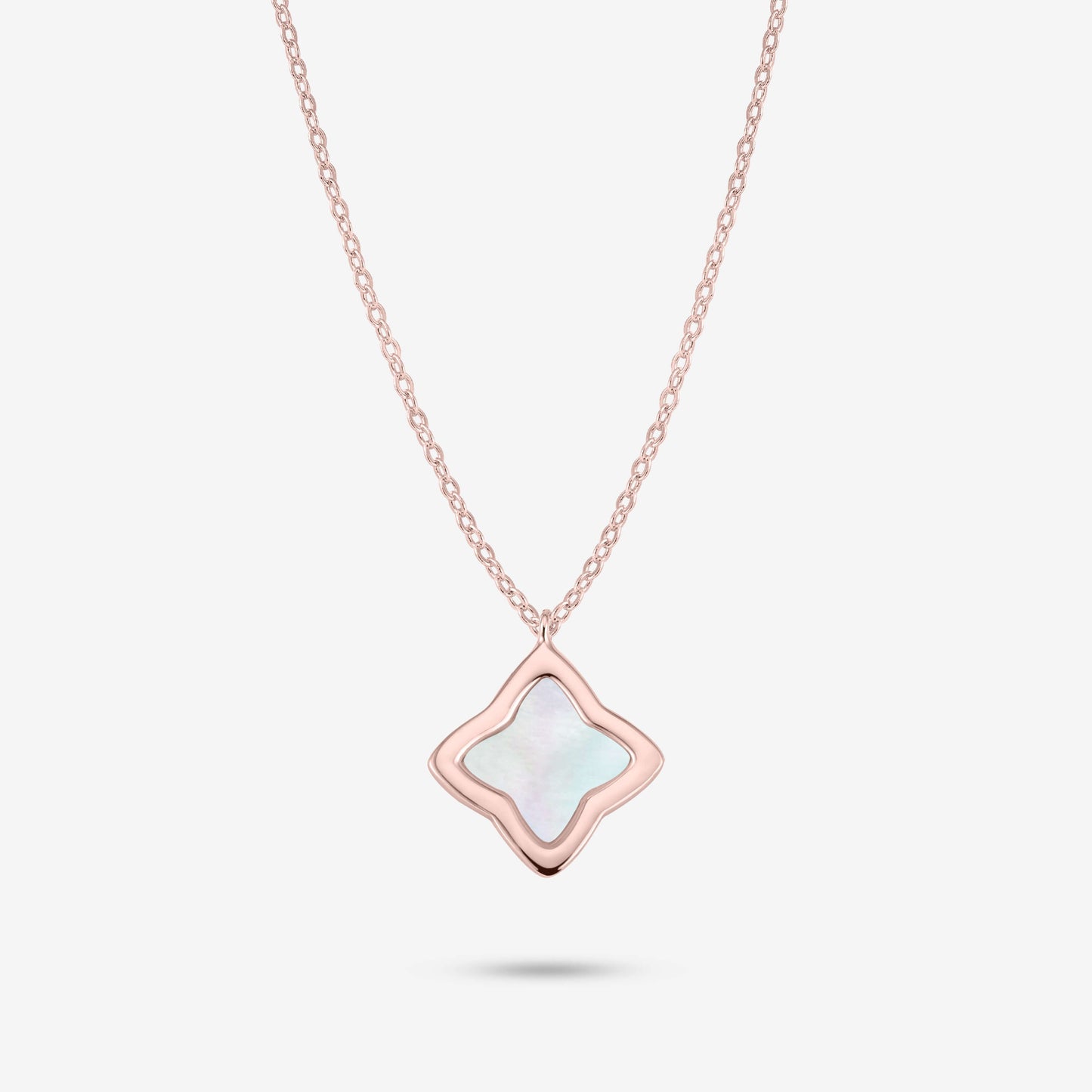 Studio shot of the Rose Gold Creia Necklace with a clover-shaped pendant and mother-of-pearl center on a grey background