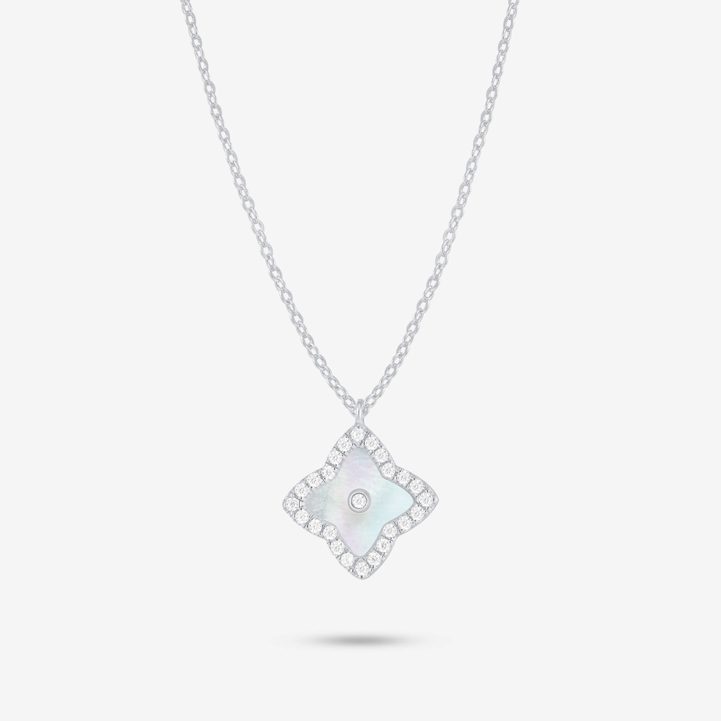 Studio shot of the Silver Irida Necklace with a quatrefoil mother-of-pearl pendant, moissanite halo, and bezel-set center stone on a grey background.