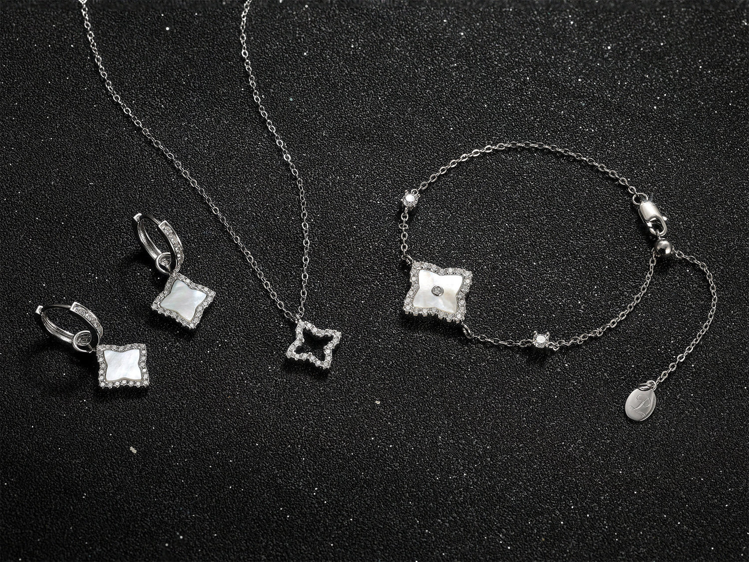 An elegant flat lay showcasing several Pure Moments signature designs in 925 sterling silver, each adorned with sparkling pavé moissanite, arranged against a sophisticated black backdrop.