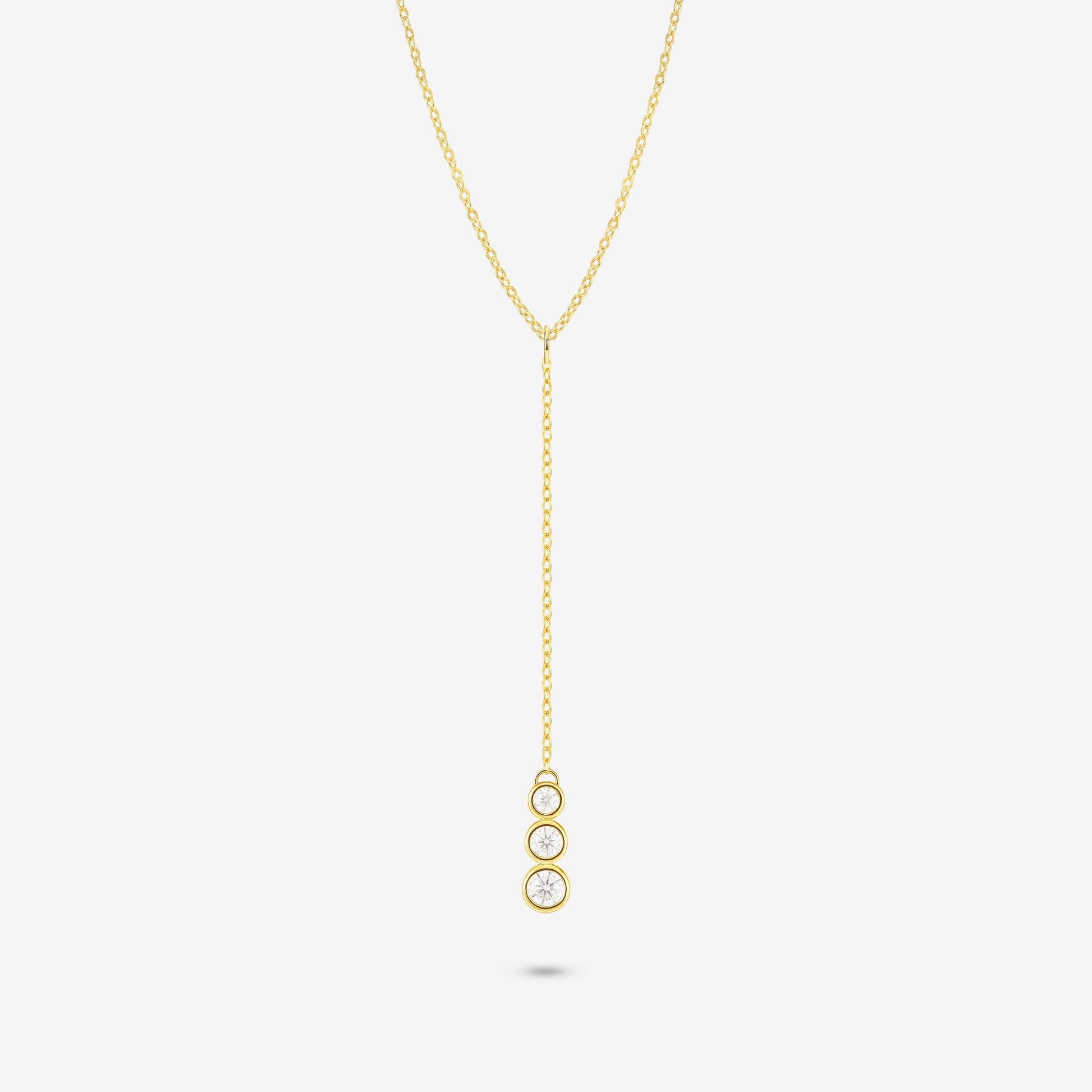 Studio shot of the Gold Astral Necklace featuring a lariat Y-necklace design with three vertically aligned bezel-set moissanites in a drop pendant on a light grey background