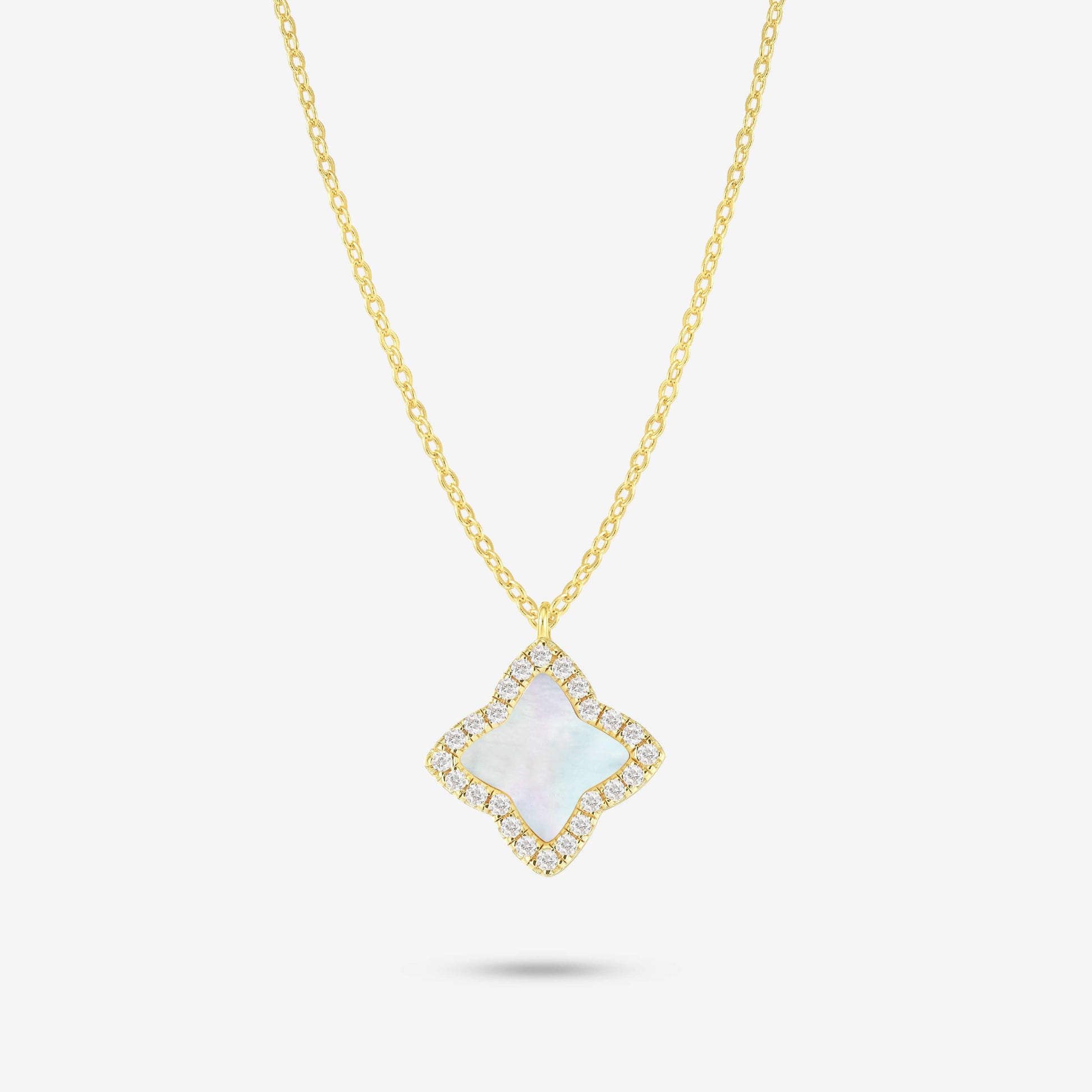 Studio shot of the Gold Edea Necklace with a clover-shaped pendant framed by moissanites and iridescent mother-of-pearl, photographed on a plain grey backdrop