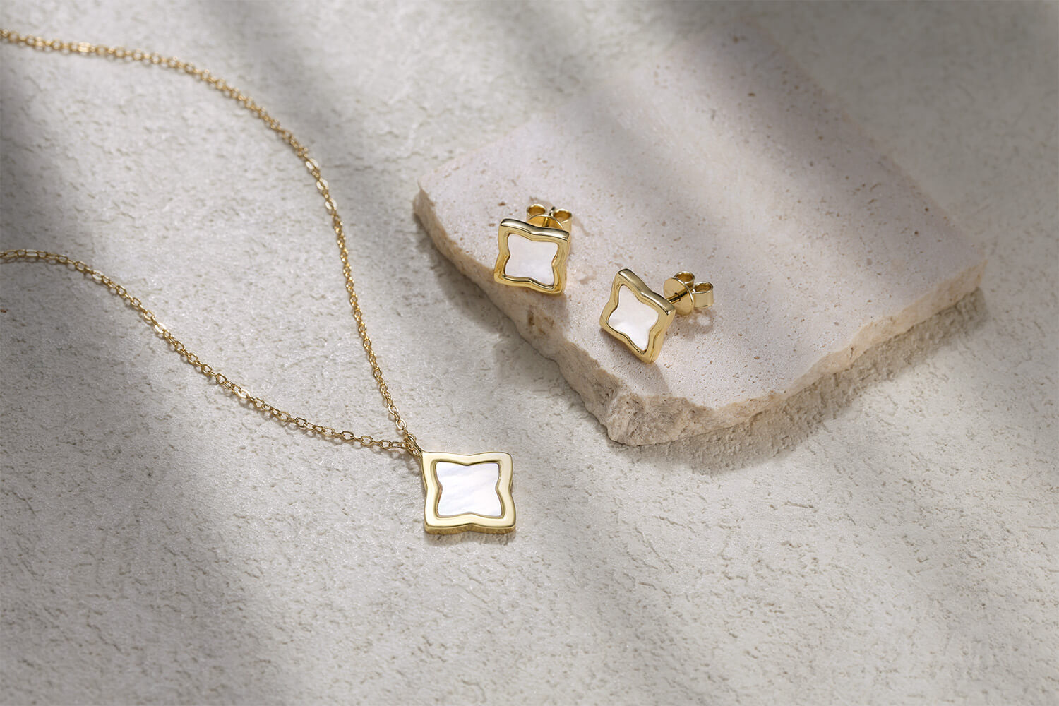 A stunning flat lay of the Pure Moments Creia jewellery set, featuring a matching necklace and stud earrings crafted in 18k gold-plated 925 sterling silver with a luminous mother of pearl inlay.