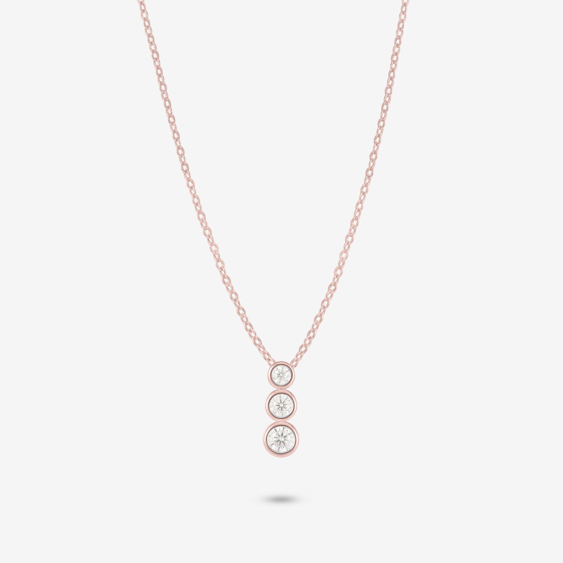 Studio shot of the Rose Gold Aviel Necklace with three graduated bezel-set moissanite stones in a pendant, photographed against a neutral grey backdrop