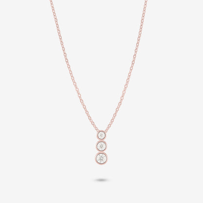 Studio shot of the Rose Gold Aviel Necklace with three graduated bezel-set moissanite stones in a pendant, photographed against a neutral grey backdrop