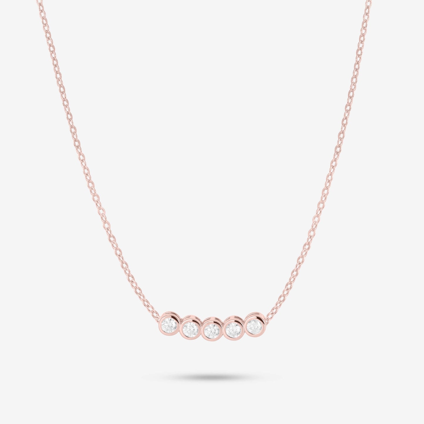 Studio shot of the Rose Gold Dawn Necklace with five bezel-set moissanites in a horizontal row on a fine rose gold chain against a neutral grey backdrop