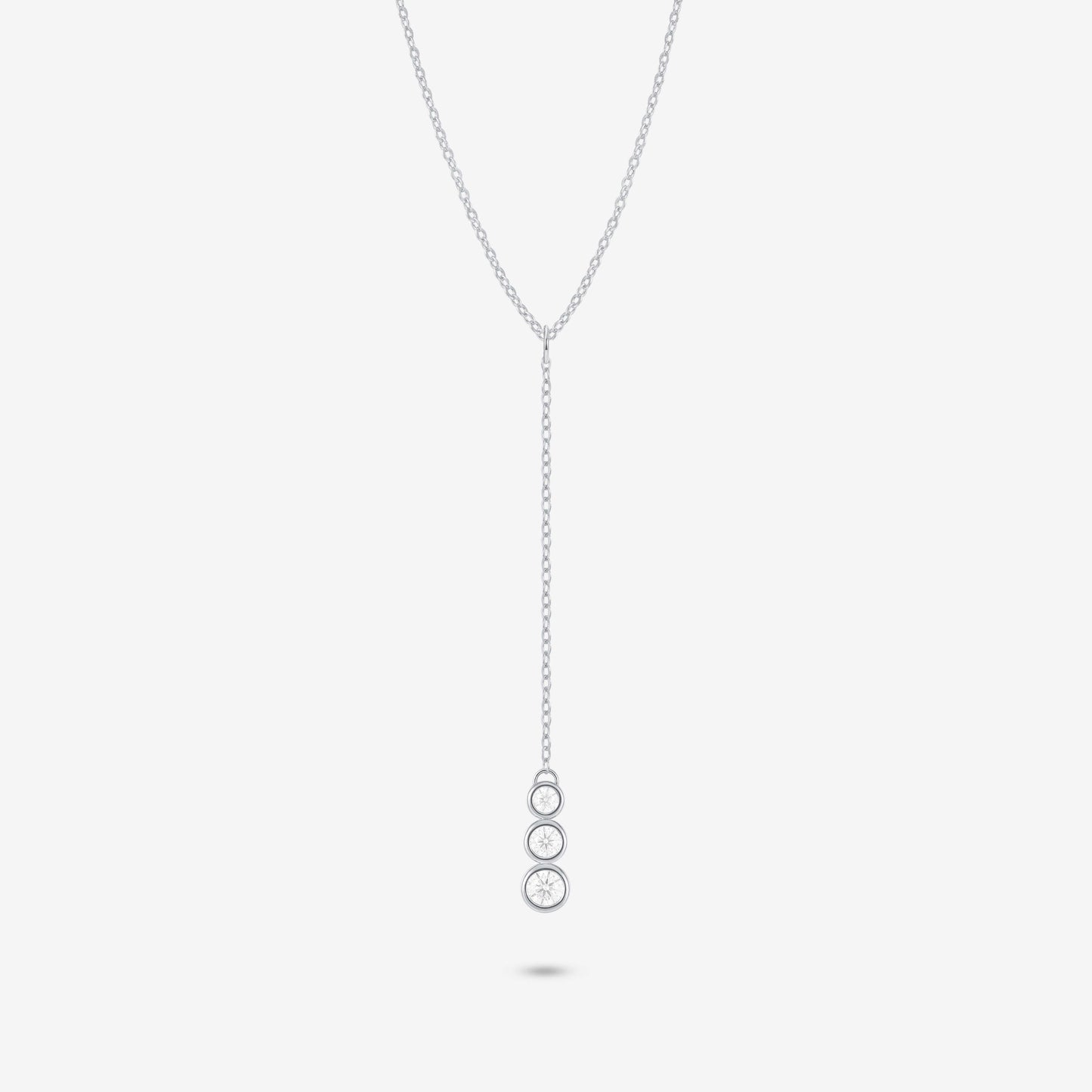 Studio shot of the Silver Astral Necklace featuring a drop pendant with three stacked round bezel-set moissanites against a pale grey backdrop