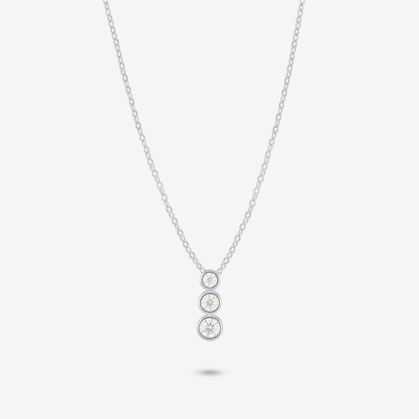Studio shot of the Silver Aviel Necklace featuring a trio of bezel-set moissanite stones in a vertical arrangement on a pale grey background