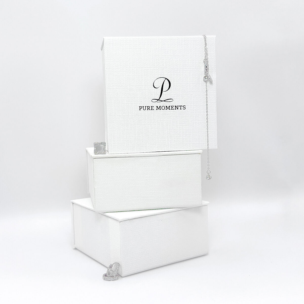 A stack of elegant white textured jewellery gift boxes together with 925 silver jewellery pieces, showcasing the premium packaging for our demi-fine jewellery.
