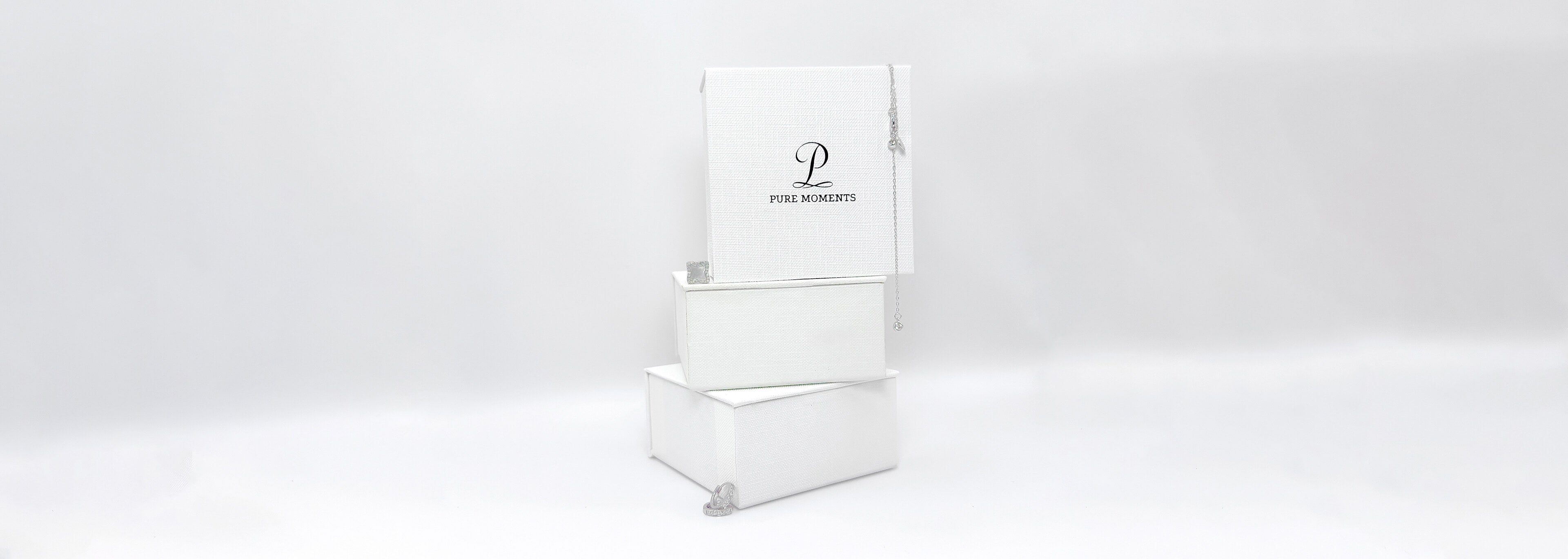 A stack of elegant white textured jewellery gift boxes together with 925 silver jewellery pieces, showcasing the premium packaging for our demi-fine jewellery.